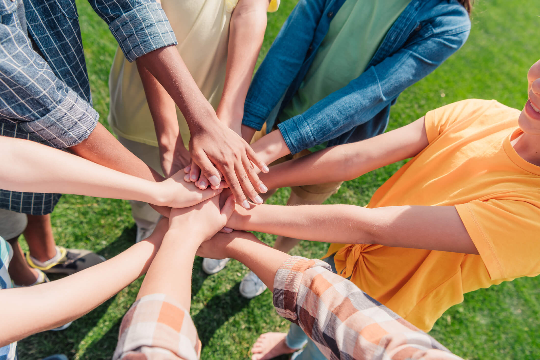 A group of people placing their hands in the middle on top of each other.