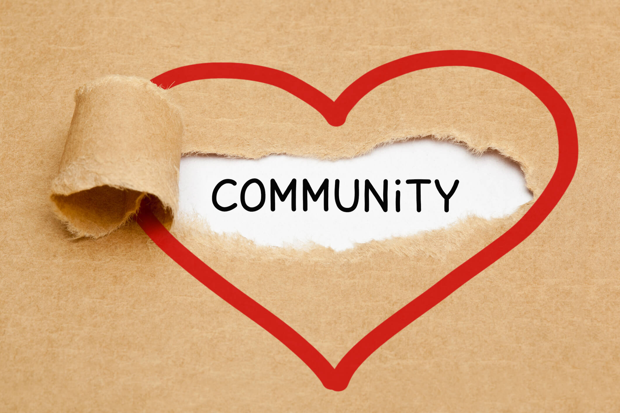 A brown paper ripped showing the word community and heart drawn around.