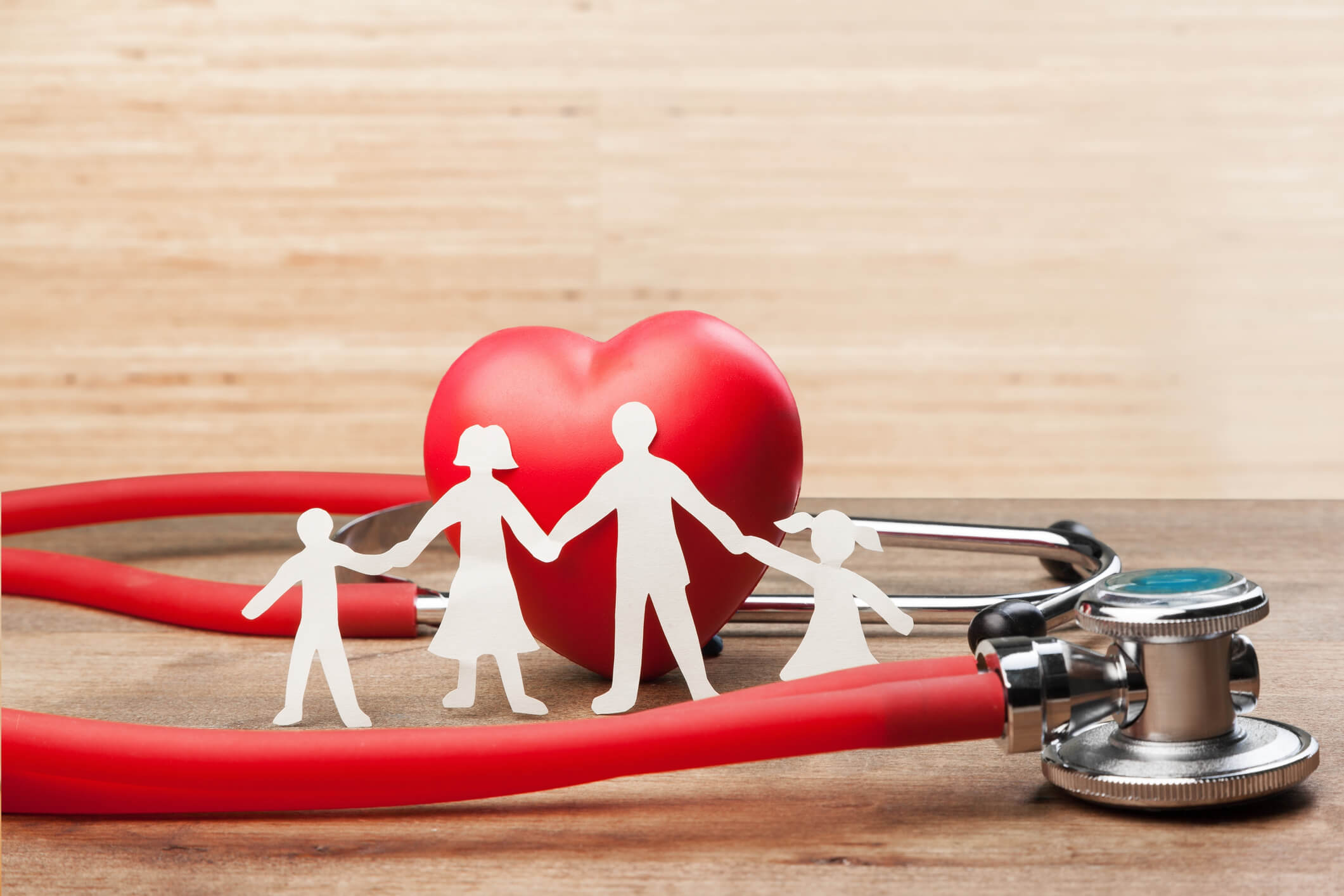 Paper figures showing a family holding hands in front of a stethoscope.